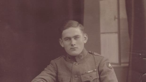 A typical portrait from the mystery studio with the painted open window. The subject of the portrait is Will Cummings, a twice-wounded Doughboy with three overseas stripes. Cummings appears to have the colored backing made from crepe paper and cardboard for his collar disks and both disks appear to be “US.” Though no rank is visible, the presence of the whistle-chain might indicate his rank as being an NCO.