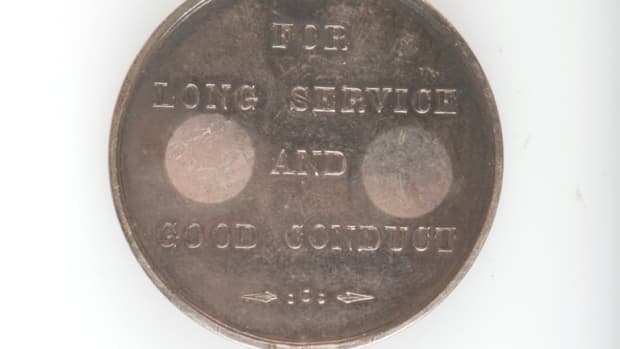 Medal planchet showing discoloration from price tags being applied to reverse.