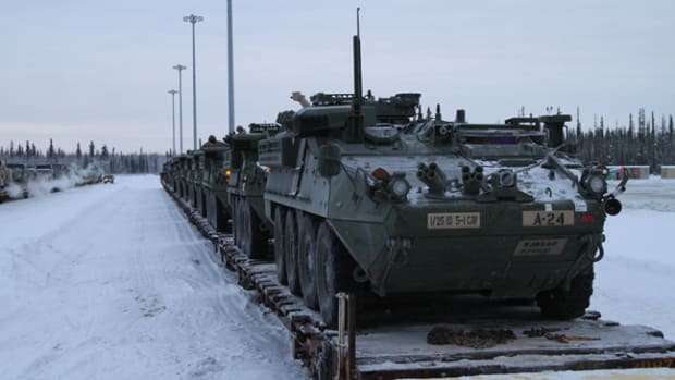 Strykers and other vehicles wait to be driven off train cars at Fort Wainwright, Alaska, Dec. 9, 2015. The return of the vehicles signals the end of the Pacific Pathways mission in Japan and Korea.