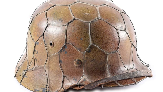 Authentic WWII German Luftwaffe M35 tri-color spray ‘chicken wire’ camouflage helmet known to collectors as a ‘Normandy’ style. Marked ‘ET68’ for the maker Eisenhuttenwerk/Herz. Luftwaffe eagle and national colors decals visible beneath camo paint. Vetted by Willi Zahn.