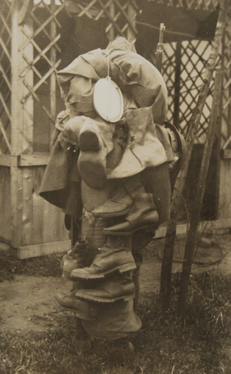 WWI soldier covered with a pile of military gear.