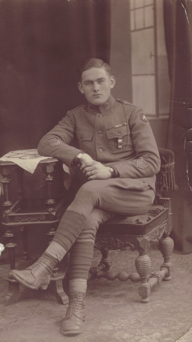 A typical portrait from the mystery studio with the painted open window. The subject of the portrait is Will Cummings, a twice-wounded Doughboy with three overseas stripes. Cummings appears to have the colored backing made from crepe paper and cardboard for his collar disks and both disks appear to be “US.” Though no rank is visible, the presence of the whistle-chain might indicate his rank as being an NCO.