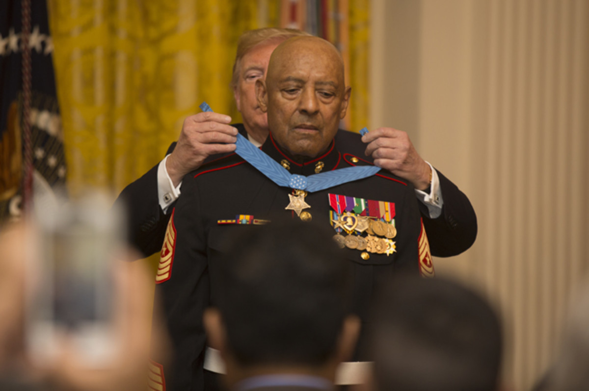  President of the United States Donald J. Trump places the Medal of Honor around retired U.S. Marine Corps Sgt. Maj. John L. Canley's neck, the 300th Marine Medal of Honor recipient, at the White House in Washington, D.C., Oct. 17, 2018. From Jan. 31, to Feb. 6 1968 in the Republic of Vietnam, Canley, the company gunnery sergeant assigned to Alpha Company, 1st Battalion, 1st Marines, took command of the company, led multiple attacks against enemy-fortified positions, rushed across fire-swept terrain despite his own wounds and carried wounded Marines into Hue City, including his commanding officer, to relieve friendly forces who were surrounded. (U.S. Marine Corps photo by Cpl. Daisha R. Johnson)