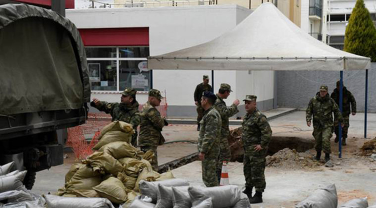 Military officers unload sacks of sand next to a hole in the ground (R), where a 250 kg World War Two bomb was found during excavation works at a gas station, before an operation to defuse it that will take place on Sunday, in Thessaloniki, Greece February 10, 2017. REUTERS/Alexandros Avramidis