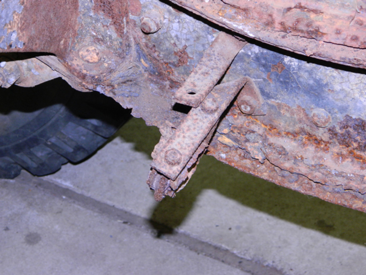 Frame rust under the cab. This damage is right behind the spring hanger. It is a high-stress area and a serious failure point if not repaired correctly.