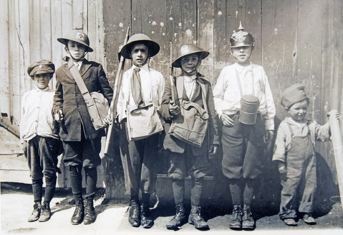 Group of kids playing army were photographed in 1920. The boy, second from the left is wearing a M1917 helmet decorated with the painted insignia of the 102nd Infantry Regiment. The boy fourth from the left is wearing a helmet that has a 101st Regiment insignia. 