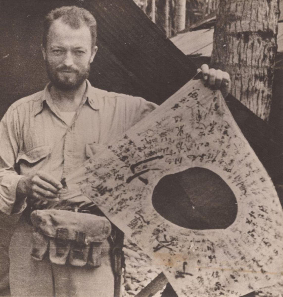  Following his rescue, Hugh Miller displays the hinomaru yosegaki flag he took from the body of one of the first enemy troops he killed on Arundel Island. Carried by the majority of Japanese military personnel in World War II, these flags were symbols of good luck given to men before they deployed. Inscribed with patriotic slogans, religious sayings and good wishes for health and success in battle, the flags were often worn wrapped around the body. (National Archives. Courtesy of Mr. Stephen Harding)