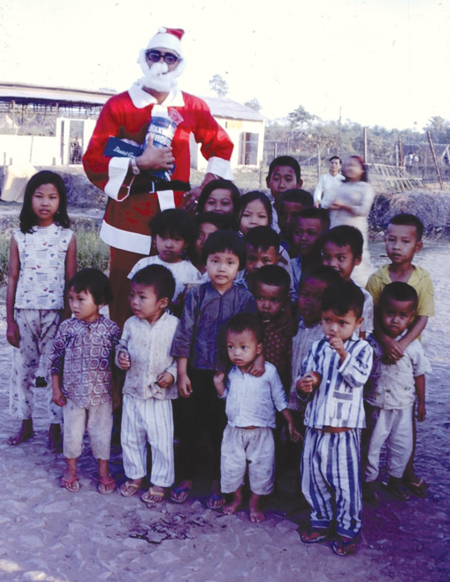 An American soldier dressed as Santa handing out candy to Vietnamese children.
