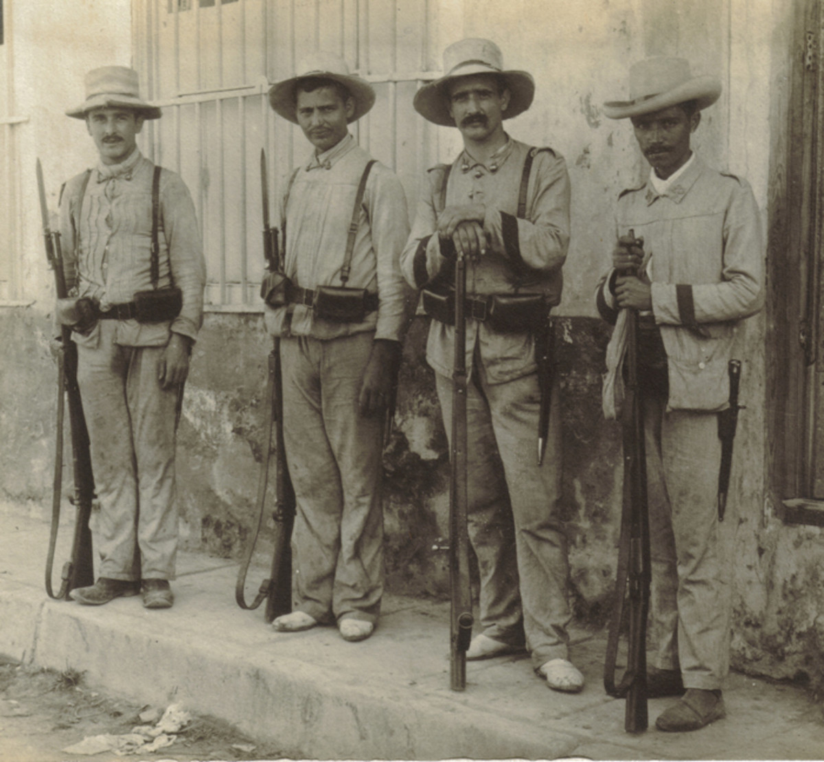 Spanish soldiers in Cuba, 1898. The Infantryman on the reader’s right is from the 38th. Regiment “León”. His three comrades are Artillerymen. All wear variations of the blue and white pin-striped cotton rayadillo uniform.
