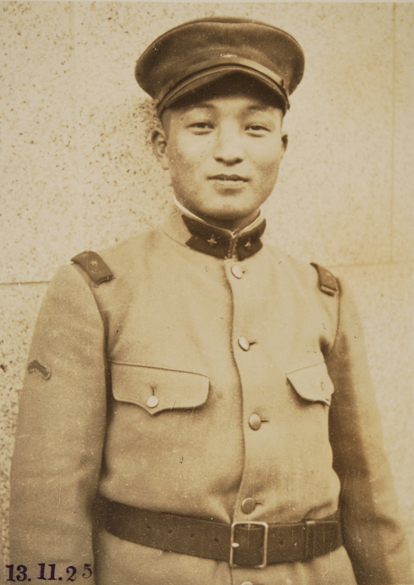 In 1930, the Japanese Army slightly modified the Type 45 tunics that it had adopted in 1911 by removing the piping from the top of the cuffs but retained the shoulder straps and standing collar with swallow-tailed collar insignia. The resulting style was designated the “Type 5 Tunic.” This Japanese Private First Class (probationary officer as denoted by collar badges) is wearing a woolen, winter issue Type 5 tunic. The patch on his right sleeve is a Diligence Badge.