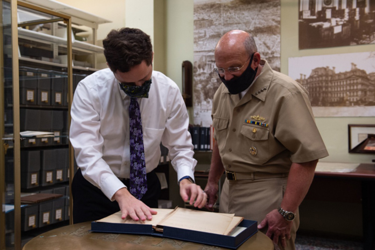 Mike Gilday and Dylan Beazer, a Department of the Navy Library librarian, view a historical navy document in the Navy Department Library’s rare book room. Gilday toured the Navy Department Library after the ground breaking of the Operational Archives and Repository Complex. NHHC, located at the Washington Navy Yard, is responsible for the preservation, analysis, and dissemination of U.S. naval history and heritage.