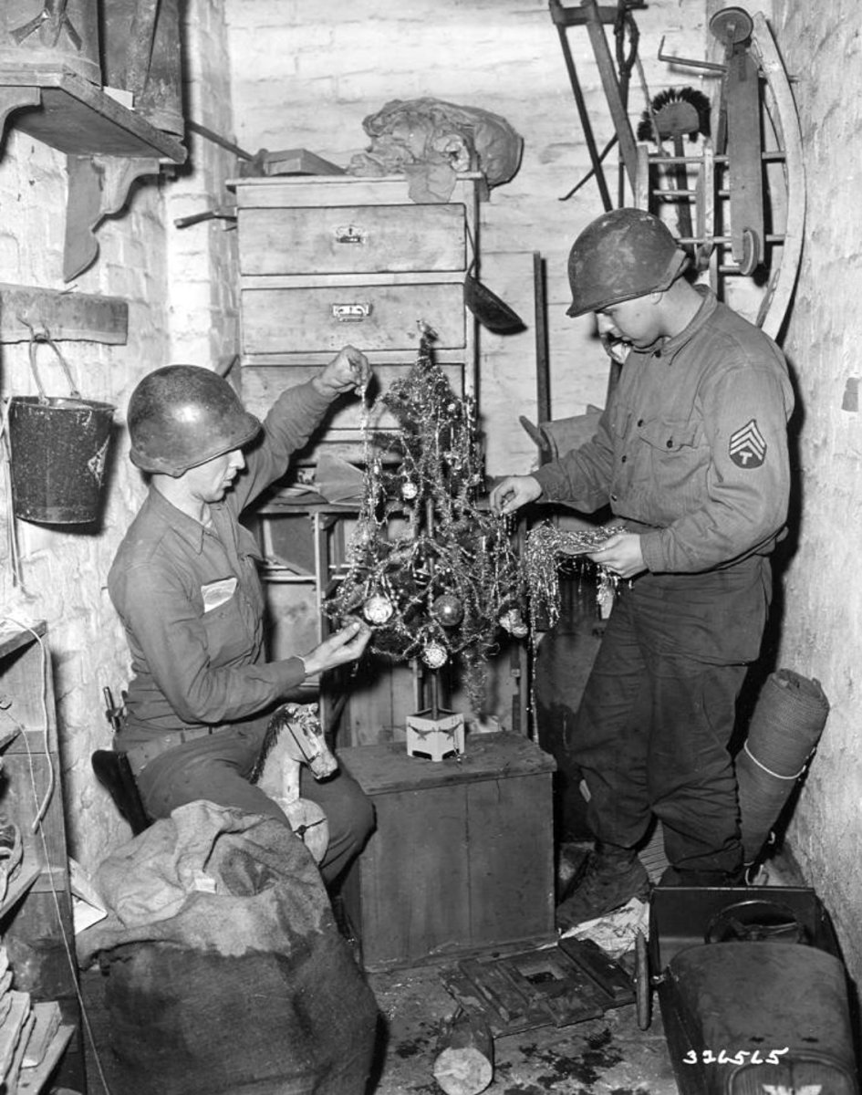 84th Training Command. Two GIs of 84th Training Command decorate a Christmas tree in cellar of a home in Geilenkirchen, Heinsberg, Germany. December 1944.