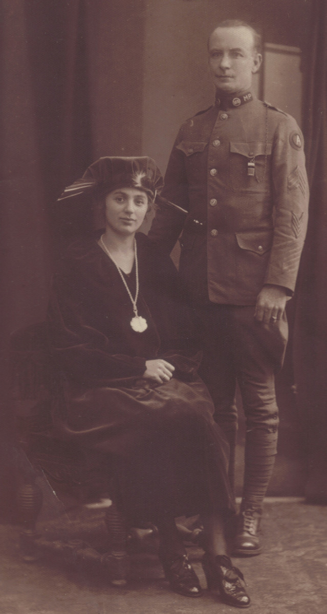 From late in the US occupation period (c.1921) this image shows a military police sergeant and a very attractive lady. While she sits in the ornate Loos chair, the sergeant is framed against the window backdrop.