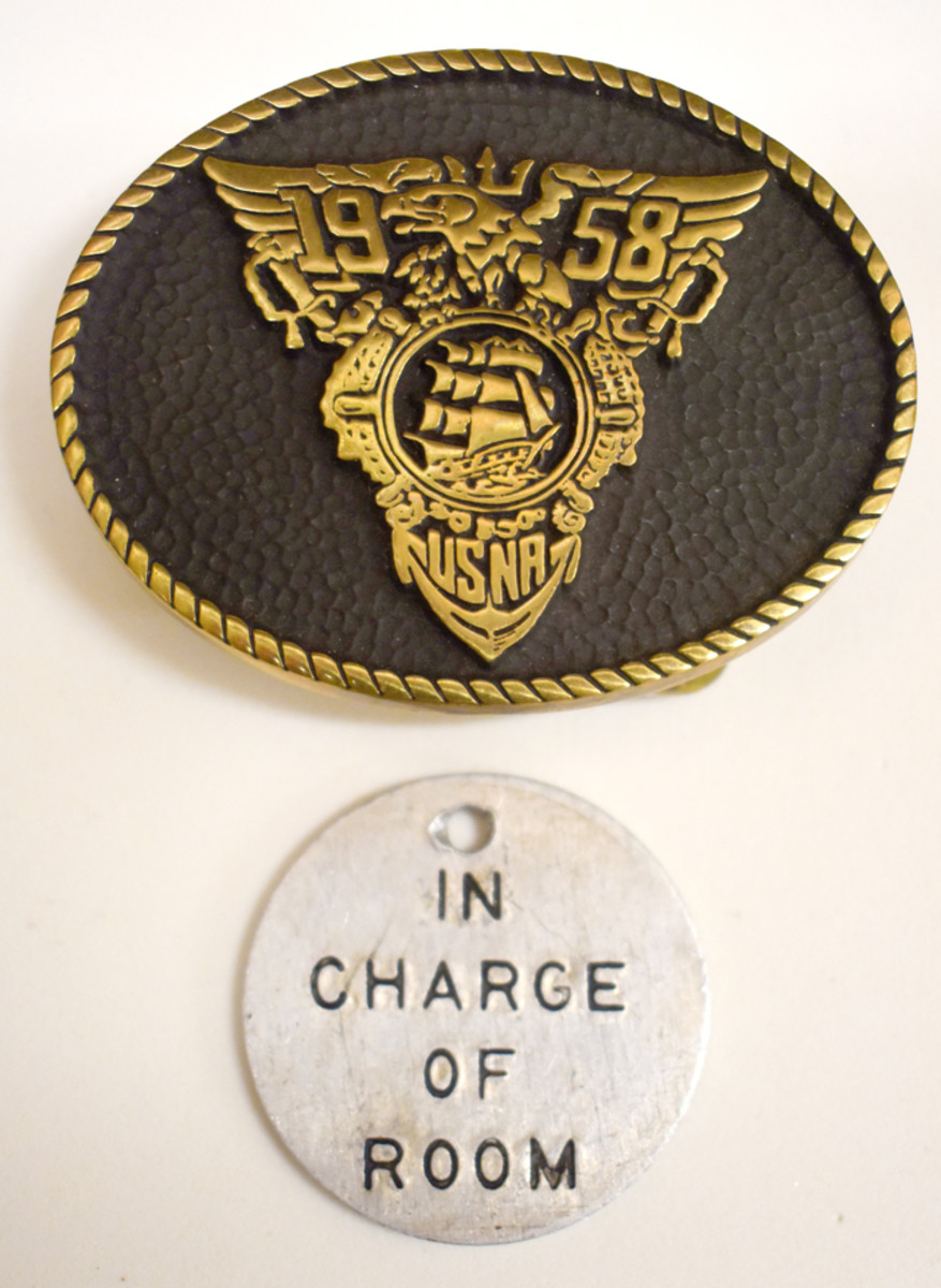 Thomas Buell’s 1958 Class belt buckle and In Charge of Room badge mark his Naval Academy experience.