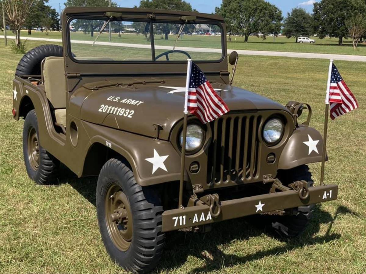 Mike Newberry's 1953 M38A1, 3/4 front view from passenger's side. Two US flags attached to front bumper that wave above the hood.