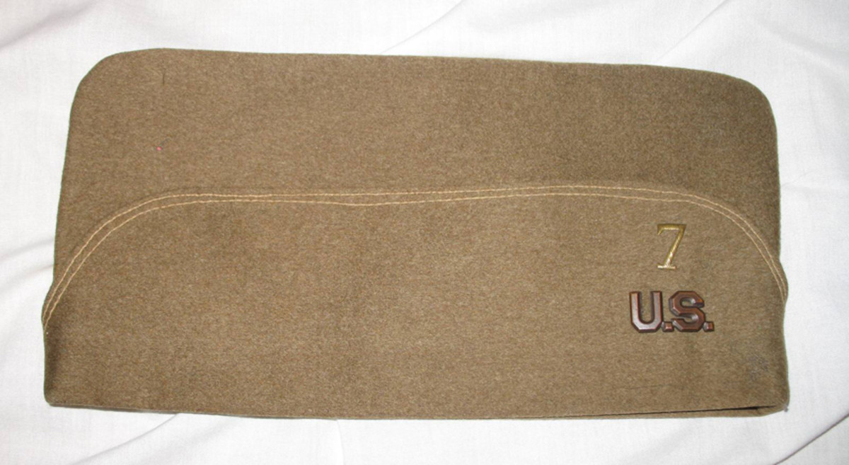 The right side of Father LeMay’s overseas cap has a bronzed “U.S.” insignia that matches the two insignia pinned to the tunic’s collar as well as a stylized French numeral “7” which was likely intended to signify Seventh Division headquarters where LeMay was assigned.
