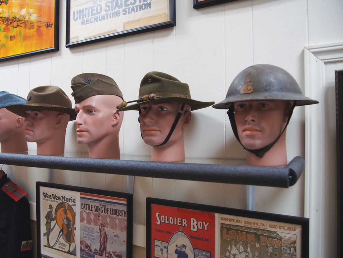 WWI Headgear is arranged among art and magazine covers of the day.