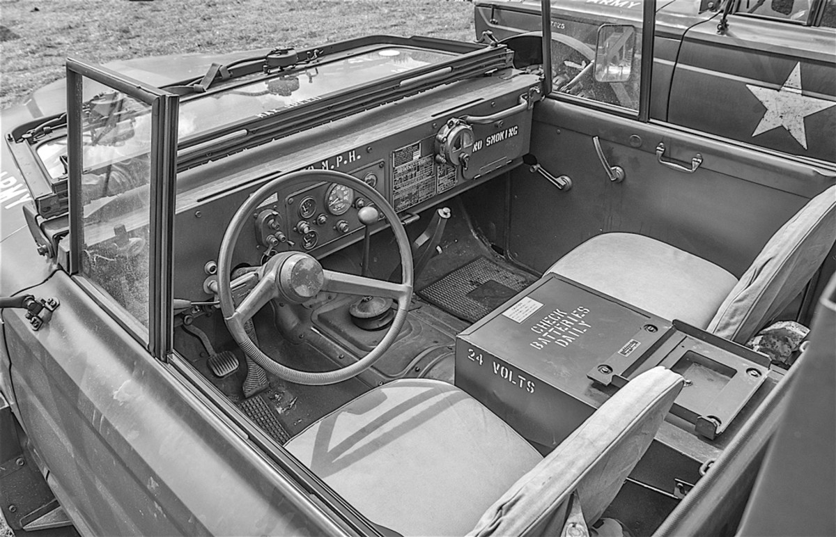 The Gladiator’s civilian streamlined dashboard was replaced with a flat military model to accommodate the standard M-series instruments and switches, and the instrument cluster was almost identical to the M37’s. The M715’s windshield was a flat, vertical, fold-down unit similar to a Jeep’s with one-piece glass, though unlike the M37, the glass itself did not open, which made the M715 a hot truck to drive in hot weather with the cab roof canvas in place. Two vacuum windshield wipers were mounted at the top of the windshield frame. The Gladiator’s civilian door glass was replaced by a different frame with a non-openable “wing window” to fit the windshield... which also added to the interior heat factor. The Gladiator’s standard bench seat was replaced with a pair of canvas-covered military bucket seats that flanked a center-mounted battery box. The battery box covers of prototype and very early M715’s were slanted forward, but were flat-topped on later units.