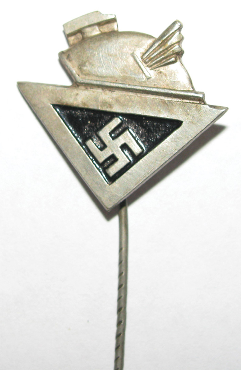 Members of Rosenberg’s KfdK group wore a pin consisting of an upturned triangle and swastika, topped with a winged helmet of the god, Mercury.