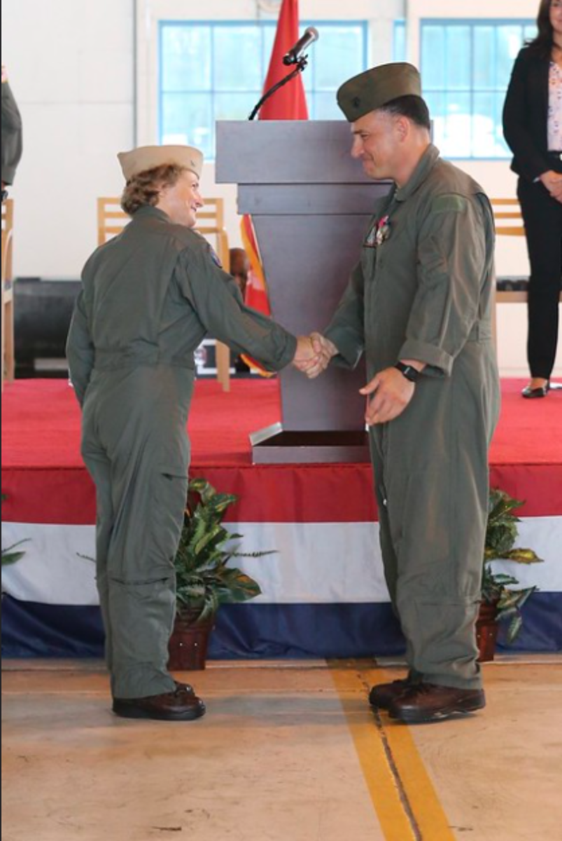 Capt. Elizabeth Somerville, left, shakes hands with Commodore Col. Richard Marigliano after taking command of Naval Test Wing Atlantic during a ceremony at Naval Air Station Patuxent River, Maryland, Aug. 11. Somerville is the developmental test wing's first woman commodore. During the ceremony, Marigliano retired from the U.S. Marine Corps after 27 years of service. (U.S. Navy photo by Paul Lagasse)