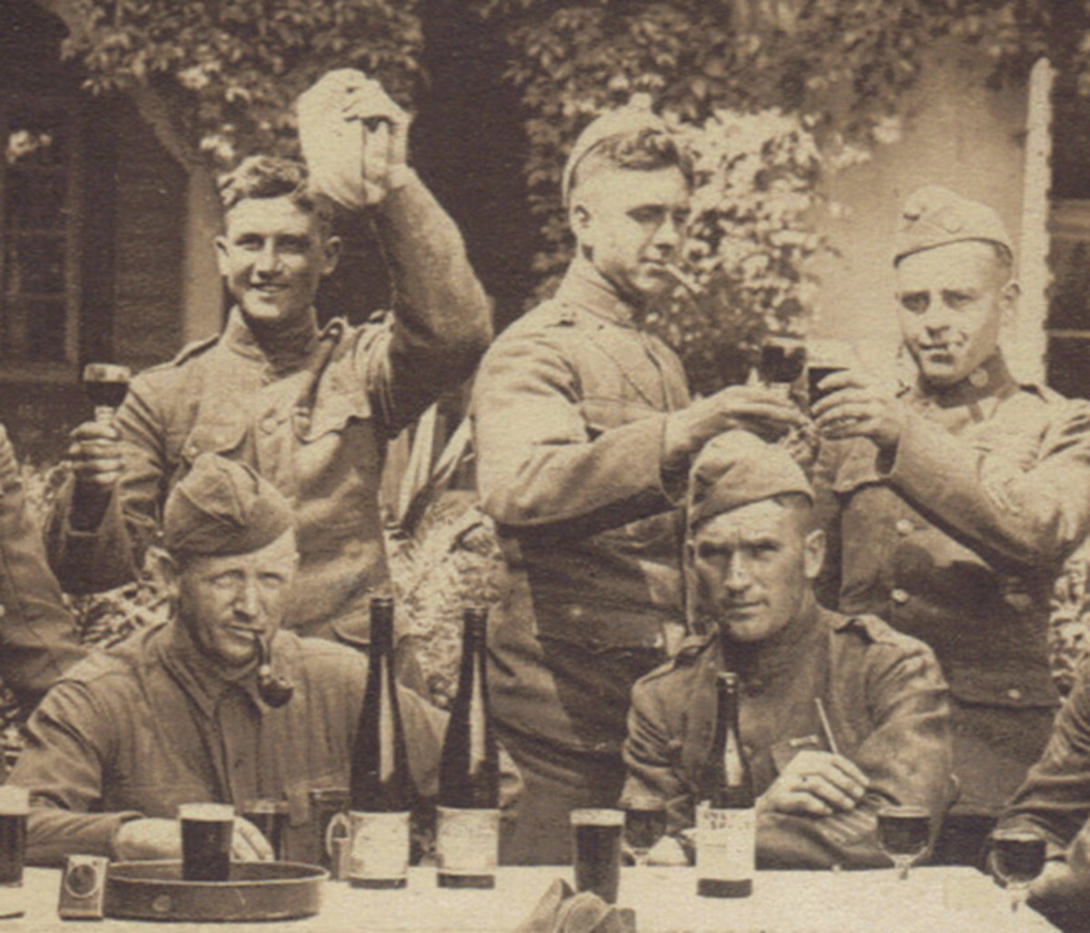 The seated soldier on the right has four overseas stripes and is ignoring the two soldiers toasting behind his head. The pipe smoking soldier on the left has leaned his tin of pipe tobacco (recognizable as Prince Albert tobacco) and box of matches against a wine bottle.