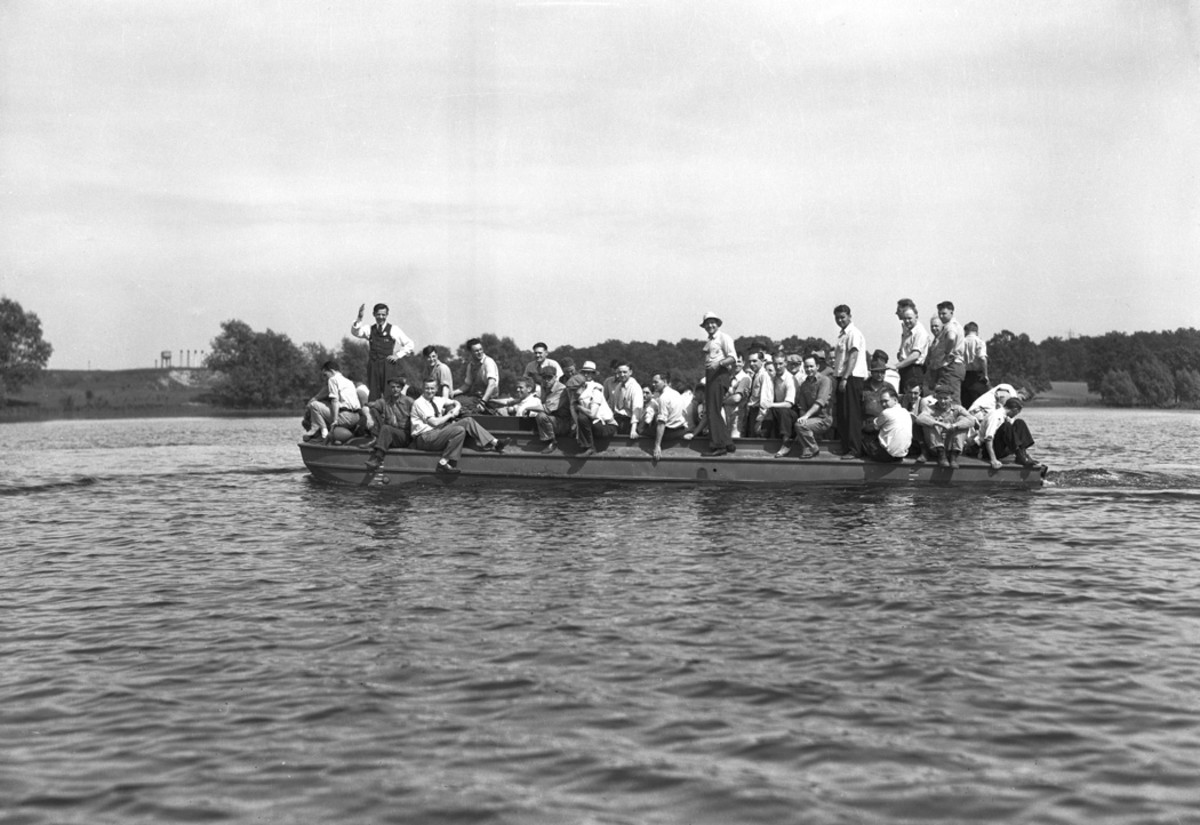 Sixty-five GMC builders and designers embark on the vehicle and go for a water ride during the preliminary trials of the first pilot DUKW. The men constituted a heavy load, and the water came up to the top rub rail, but they enjoyed a safe and  successful ride.