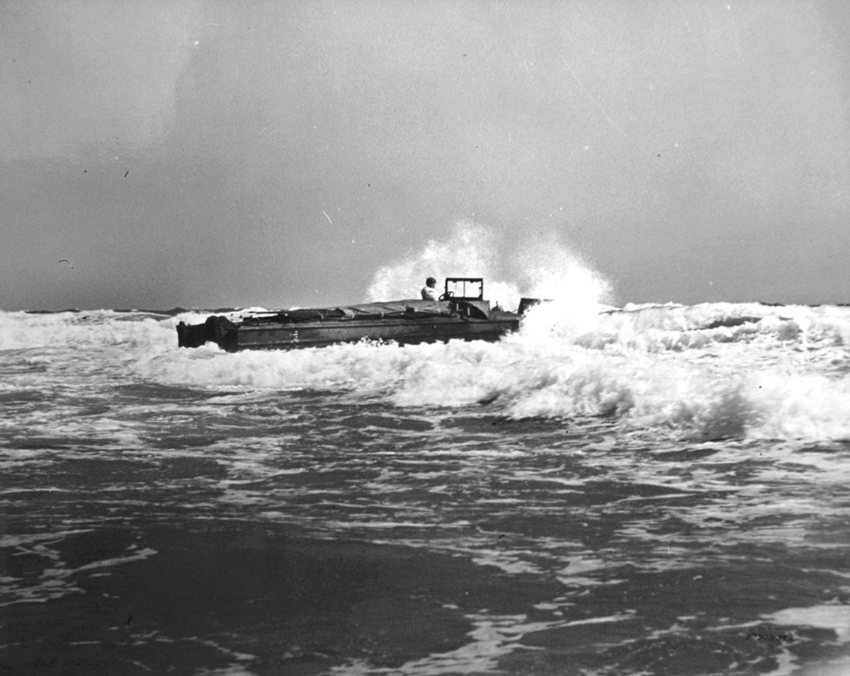 The pilot DUKW braves a heavy surf at Kitty Hawk on June 24, 1942. The vehicle was carrying a load of 3,000 lbs. and was fitted with a makeshift canvas cover for its cargo compartment. The vehicle would soon encounter trouble.