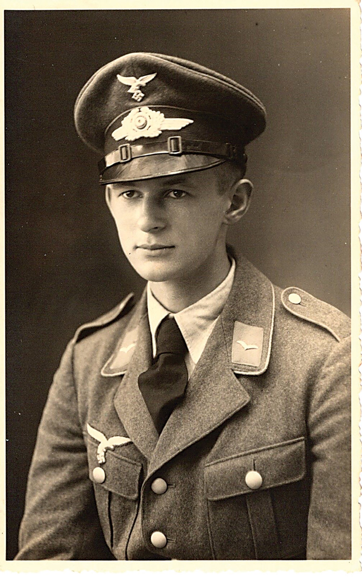 a studio portrait of a Luftwaffe soldier shows his visor eagle with down swept tail and shorter wingspan. His tunic displays an early “drop tail” eagle on the right pocket.