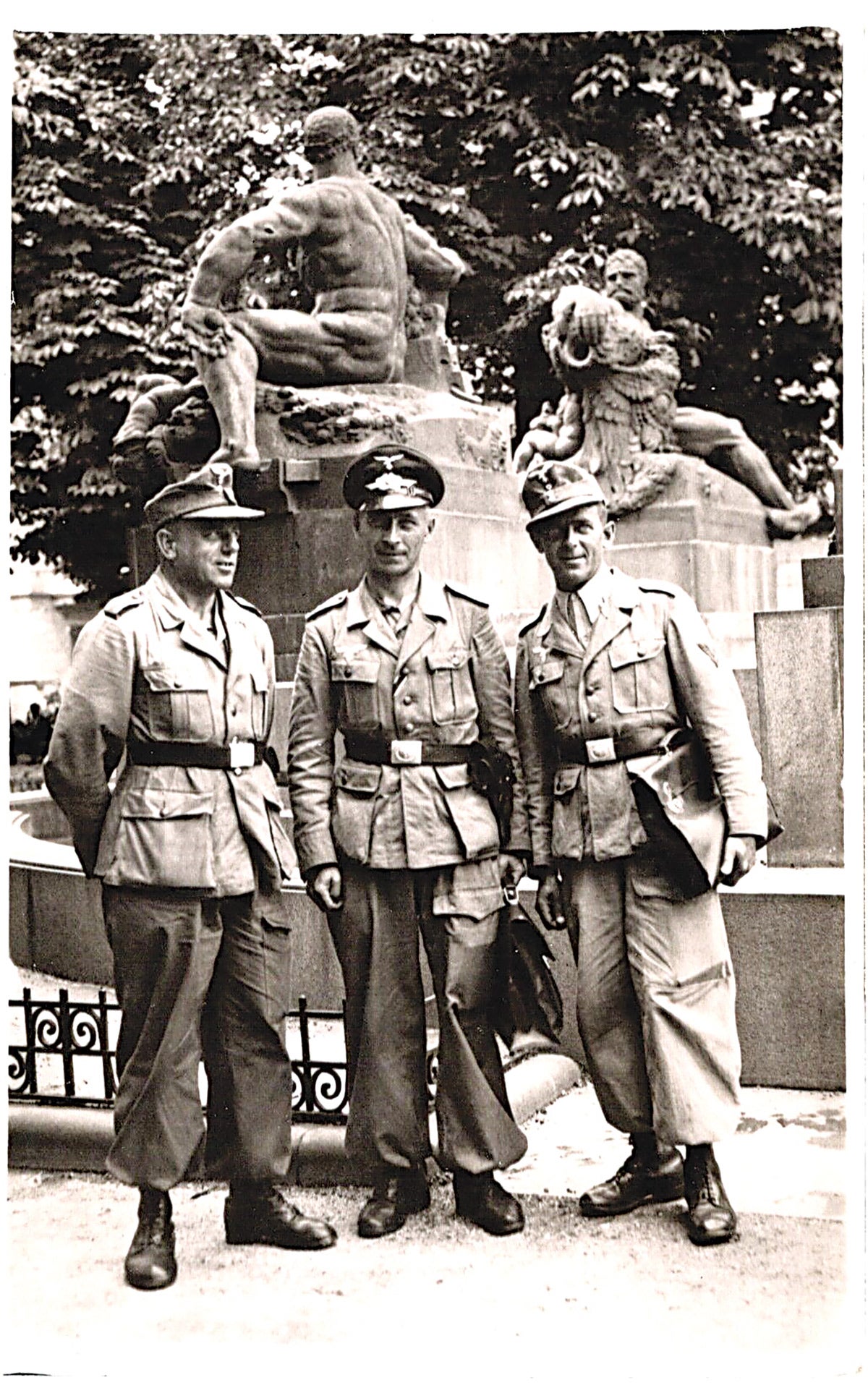 Three soldiers pose in their desert corps uniforms. The man in the center wears a traditional enlisted visor, while the men on either side wear their light-colored M43s.