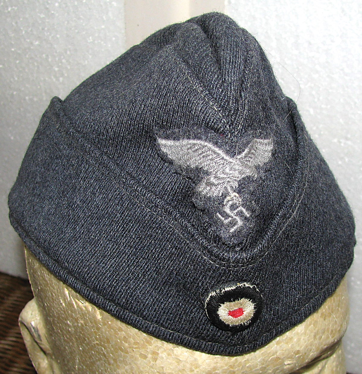 The standard enlisted Luftwaffe overseas cap in blue/grey wool with cotton eagle and swastika over the national three-color roundel.