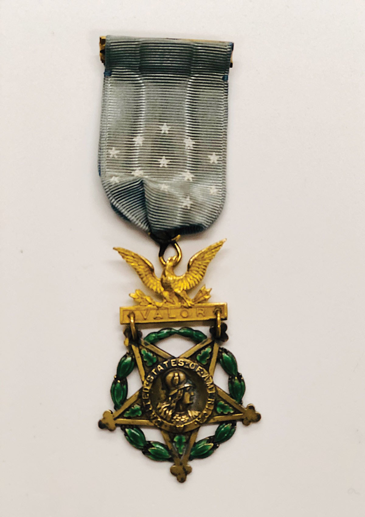 The obverse of a type IV Army Medal of Honor is a five arm star imposed on a green wreath and an eagle brooch inscribed “Valor”.