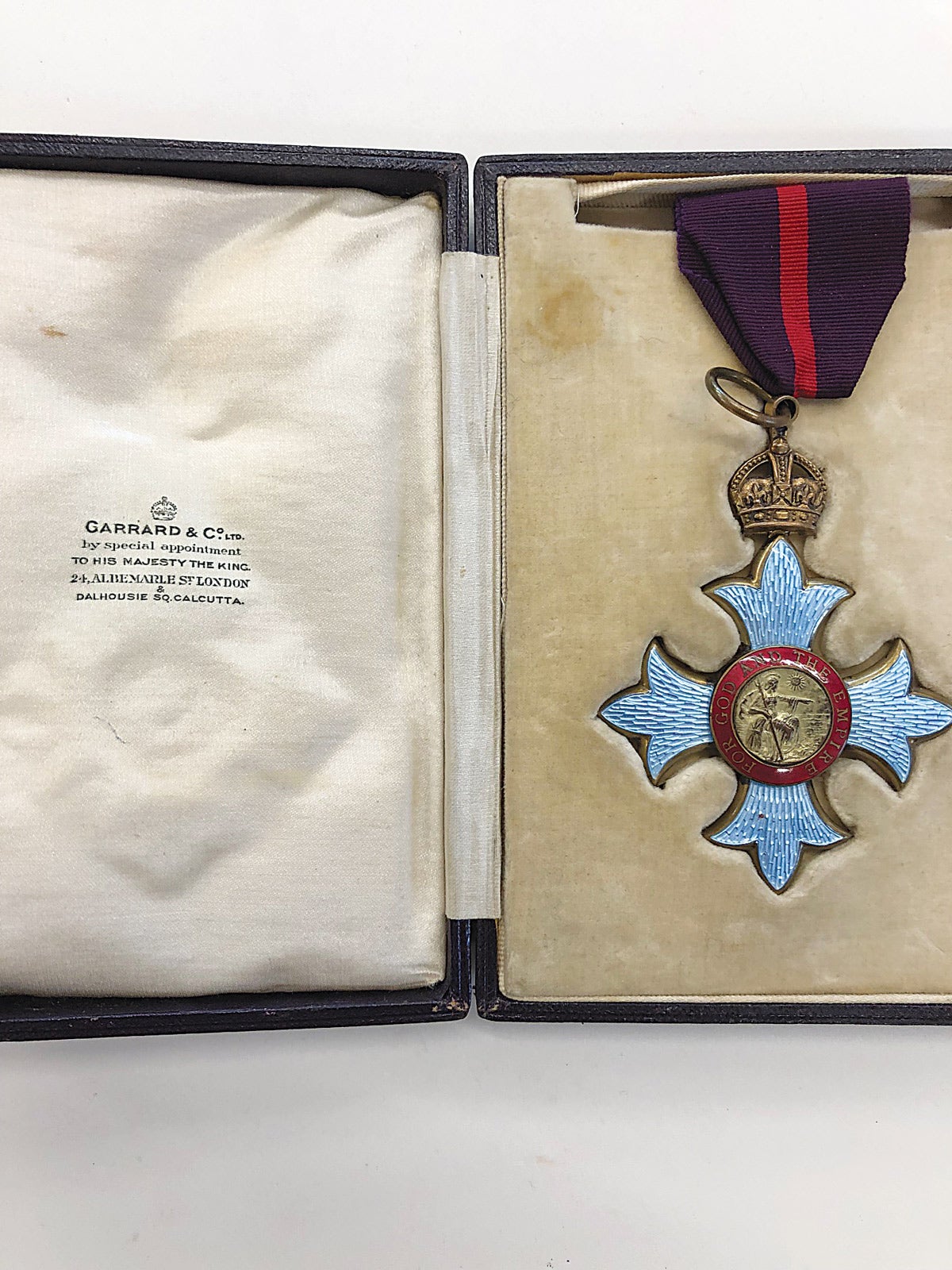 The military version of the Commander form of the Most Excellent Order of the British Empire exhibits a crown suspension to a red striped, maroon military neck ribbon.
