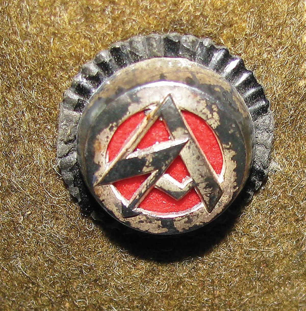 The SA-Wehrmannshaft wool cap’s roundel has the distinctive silver colored Wehrmannshaft SA symbol backed by red material and surrounded with a black border. As with many German cap devices of the period, the white, red and black signify the national colors of both the old Imperial Germany and the new Third Reich.