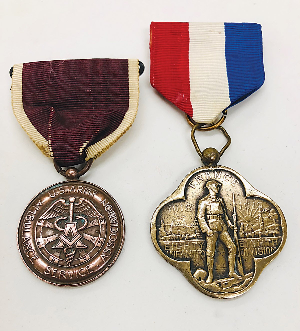 The U.S. Army Ambulance Service Association medal’s reverse shows service in France, Italy, and America with dates 1917-1919. The 88th Division medal’s reverse is plain.