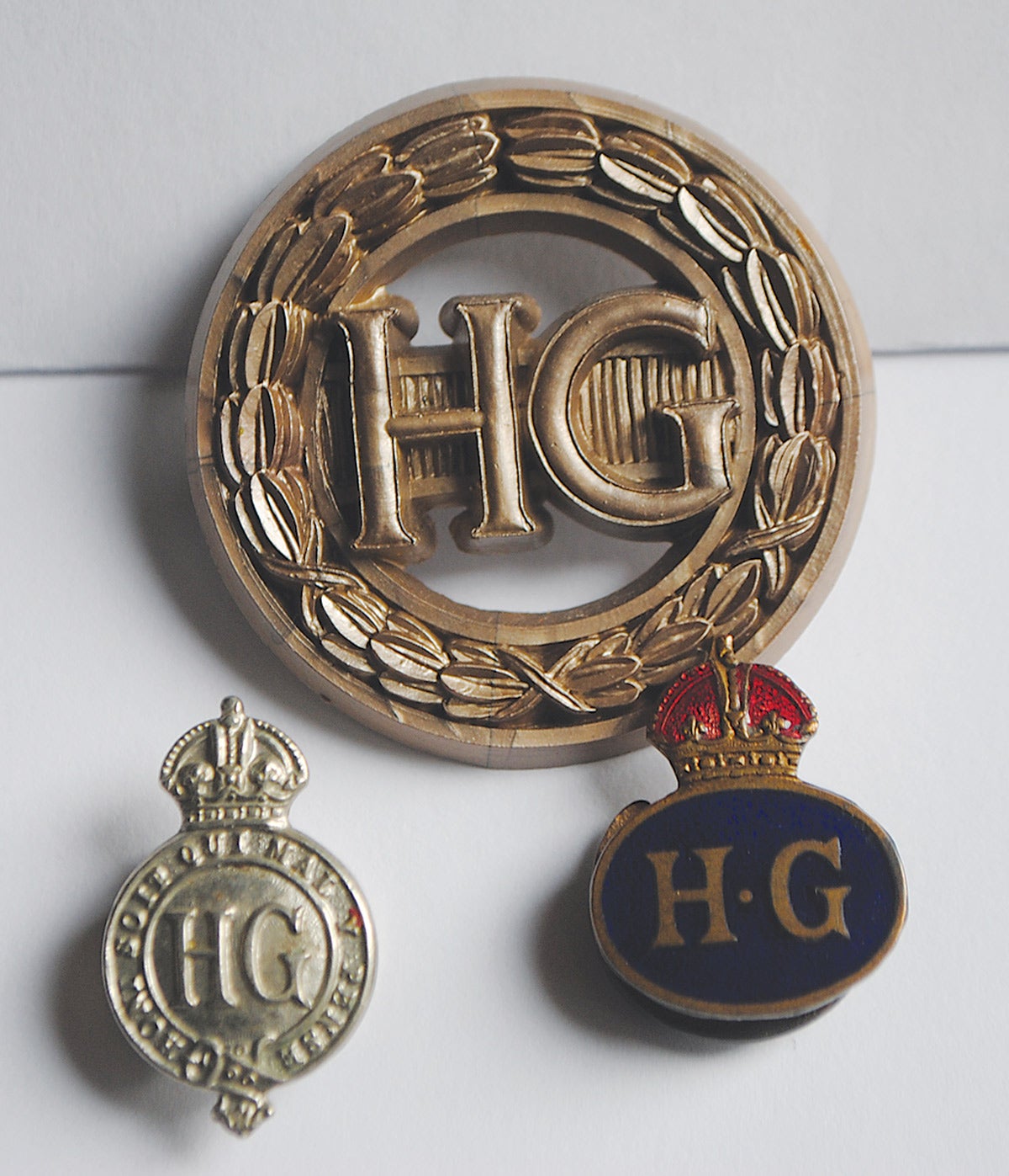 A trio of Home Guard badges worn when not in uniform. The circular brooch-like design is the ladies badge. The two lower items are variations worn by male members of the Home Guard.