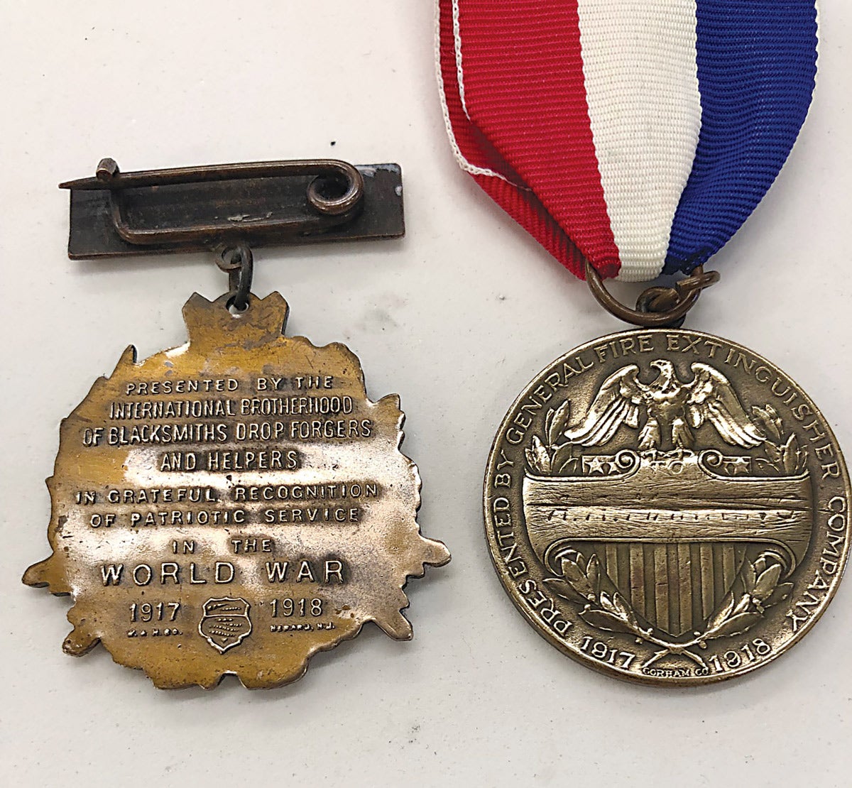 The reverse of the Blacksmith medal shows the Whitehead & Hoag maker mark and the General Fire Extinguisher’s maker mark is of the Gorham Company.
