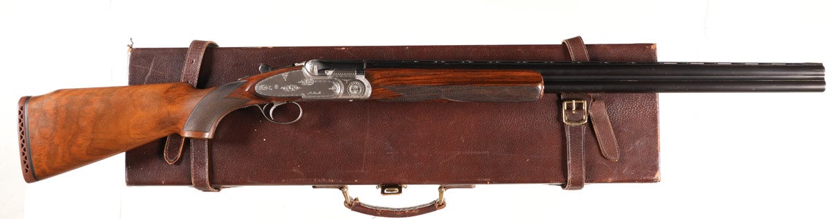 Beretta SO4 Trap 12-gauge over/under shotgun, Serial #37996, true side lock manufactured in 1969 with 29in tapered-vent rib barrels, 2¾in chambers choked Full and Modified. Single selective trigger with ejectors. Coin-finished receiver and locks with light scroll engraving. Varnished checkered pistol grip walnut stocks with factory Beretta pad. The SO4 model is widely considered one of the finest available over/under shotguns, even used by the celebrated American author and sportsman Ernest Hemingway. Very fine, 97% barrel finish with some edge wear. Brilliant bores. Receiver excellent and tight on face.  Stocks very fine with some light impressions and finish thinning at wrist. Mechanically excellent. Comes in partitioned leather travel case