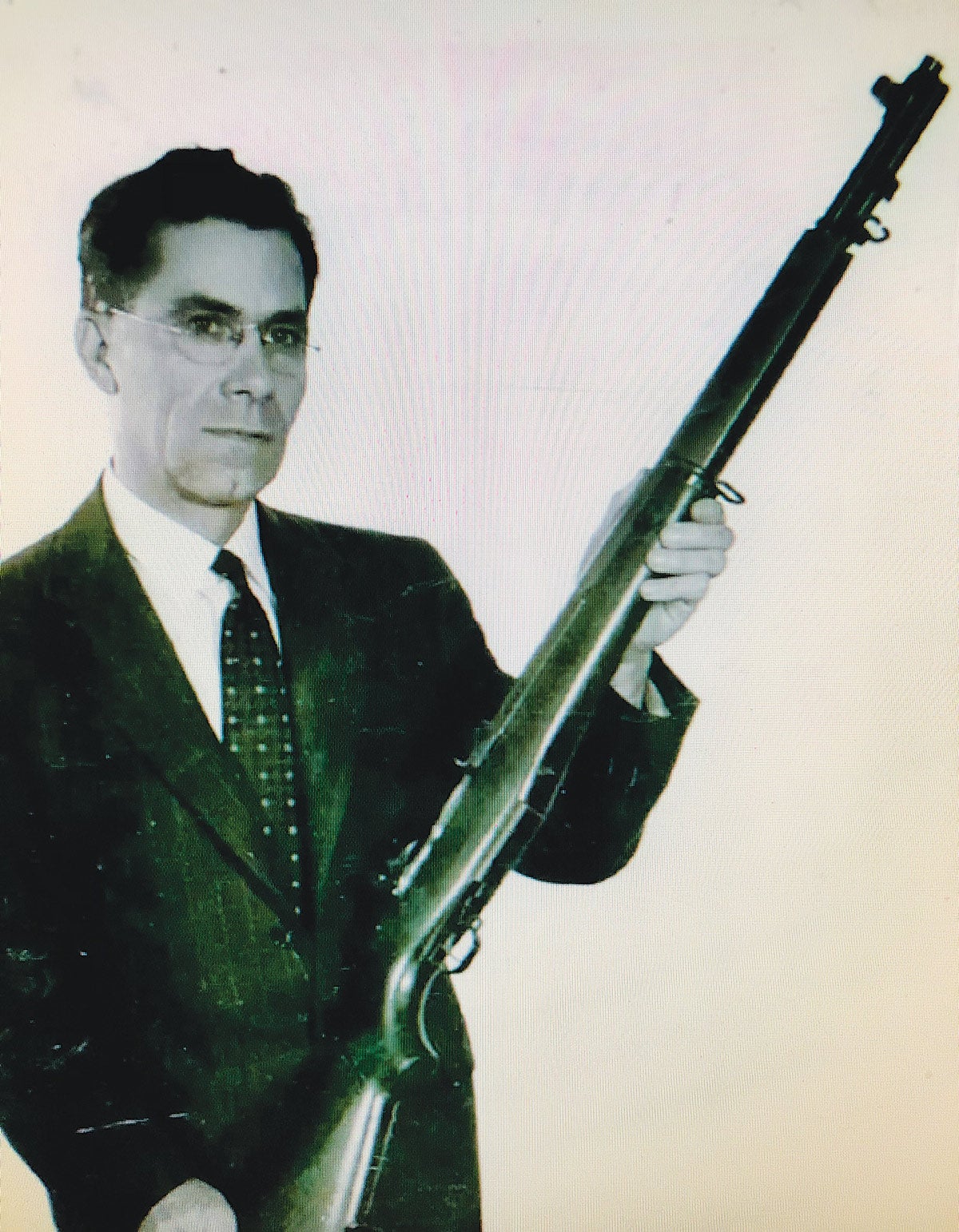 John C. Garand is seen holding his famous M-1 Garand rifle.