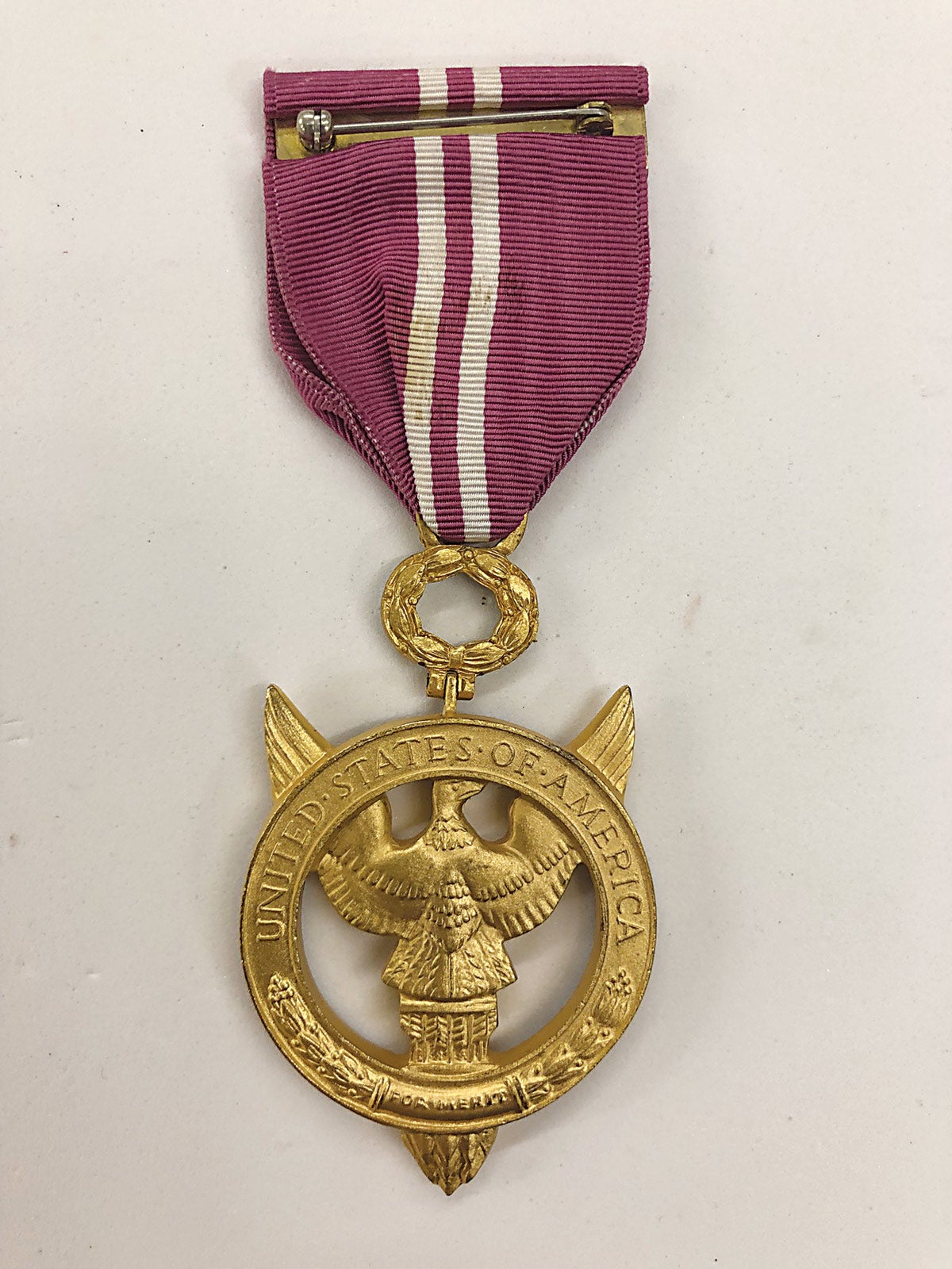 The gold ring directly below the eagle is inscribed “For Merit”. The Ribbon exhibits a crimp brooch with no maker mark.