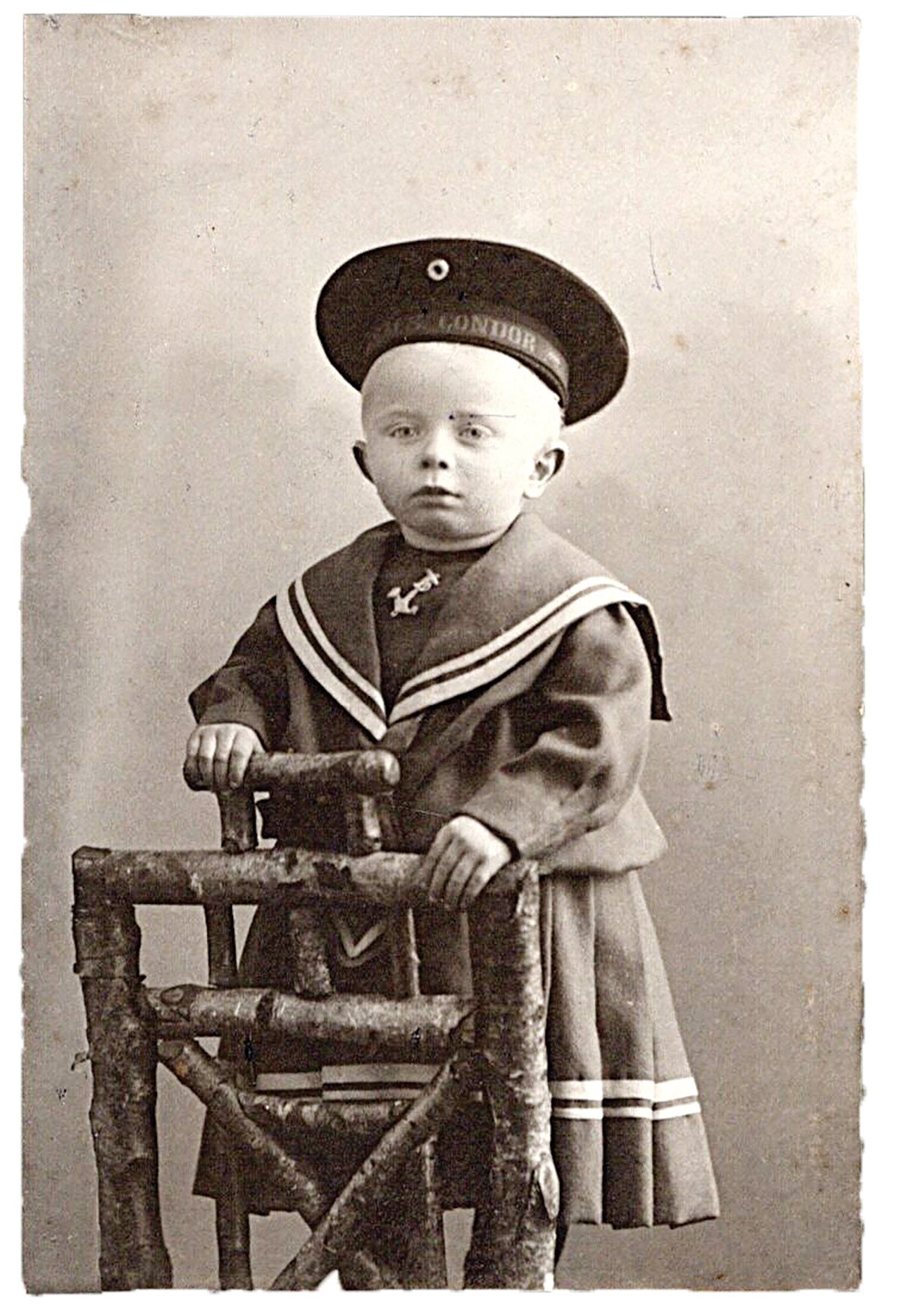 Officers’ children could wear uniforms to honor their fathers and the naval service. This young boy wears a dress (as was the European custom of the time to age 3 to 4 years old) with a sailor bib and named (“Condor”) cap.