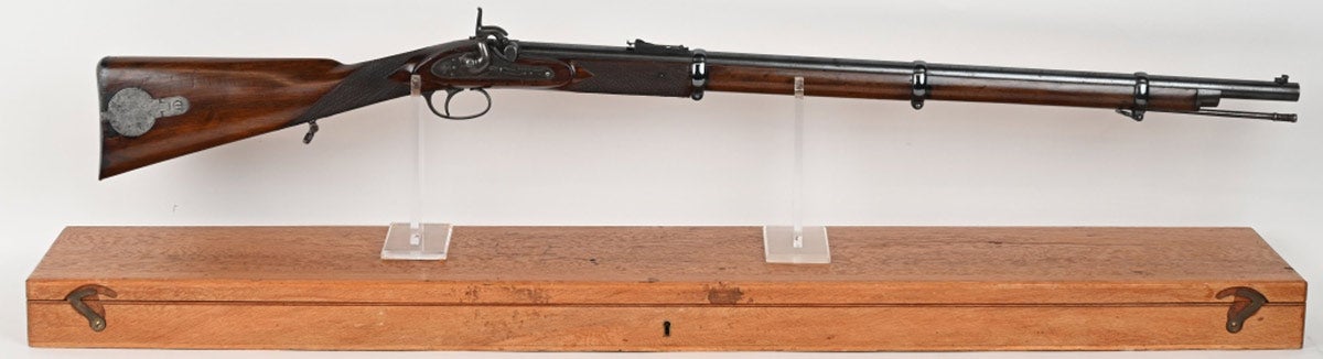 Whitworth percussion rifle manufactured 1857-1865, of a type used by Confederate sharpshooters during the Civil War. Adjustable blade front sight, notch and ladder rear sight; barrel with Birmingham proofs and ‘52’ bore marking. Serial number ‘B353’ on left at breech. Marked ‘Whitworth Patent’ on top of barrel. Crowned ‘W’ trademark and ‘Whitworth’ markings on lock, which has half-cock safety. Military-style stock, checkered at the wrist. Includes wood case with contemporary Whitworth Rifle Co. label, leather sling, bullet mold, other accoutrements. Condition: Fine with 70% period refurbished blue finish, smooth gray and brown patina on lock and furniture. Legends are crisp. Action works well, as does the half-cock safety.