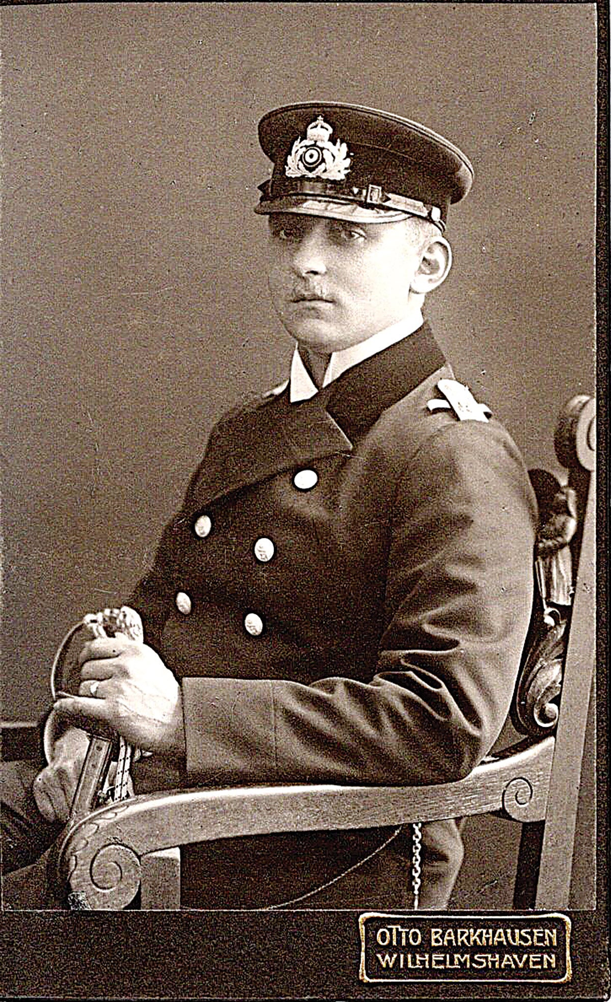 A wonderful studio portrait of a wartime naval officer, resplendent in his proper coat and imperial visor, with his lion’s head sword resting on his knee.