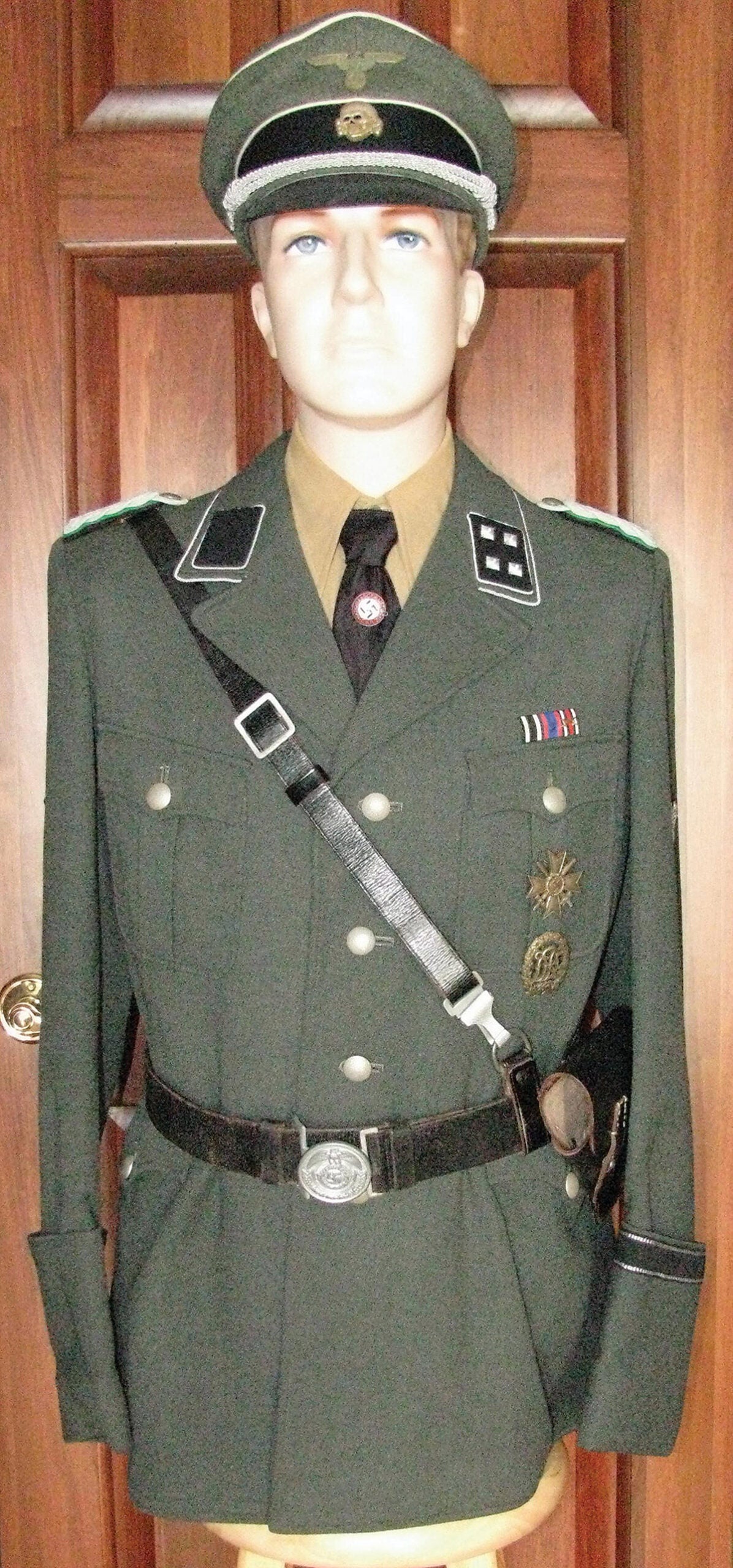 An attractive, yet menacing SD gray green Waffen-SS style uniform complete with correct shirt, tie, belt, cross strap, awards, and topped off with an excellent SS visor cap.