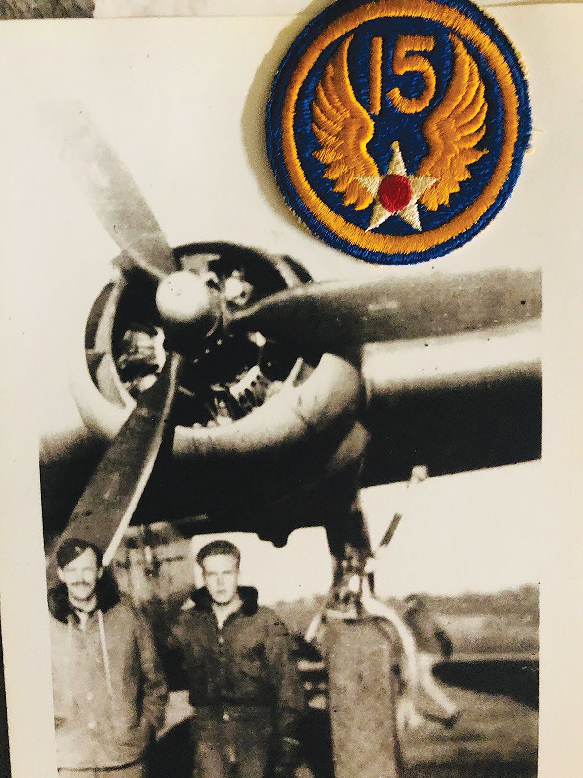 Oscar Ward Sutton of the 15th Air Force in his flight jacket under the prop of a WWII bomber.