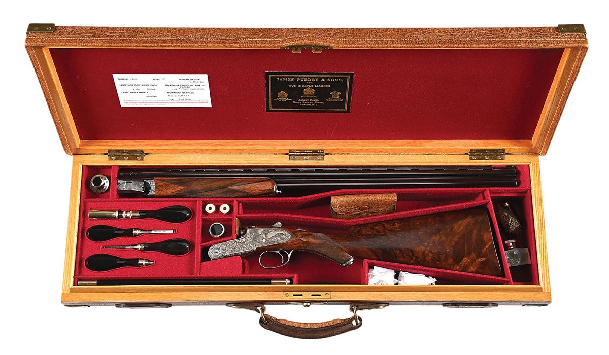 Cased 28-bore J. Purdey & Sons over-and-under ejector game gun with 28in file-cut vent rib barrels, Prince of Wales stock with blackleaf scroll and game-scene vignettes by master engraver Giancarlo Pedretti. Full-length bottom strap with gold-inlaid serial number, engraved grip cap, single non-selective mechanical trigger on round bar action, auto-safety, hold-open top lever, drop points, single small front bead, gold inlaid ‘SAFE’ by the beetle-style safety catch, gold inlaid serial number on the bottom strap, gold-lined cocking indicators, vacant gold oval on the toe line, wraparound checkered wrist with mullered borders, checkered forend with mullered borders, and Anson push-button forend release. Housed in brass-cornered oak and elephant hide presentation case with French blocked accessories having buffalo-horn handles.